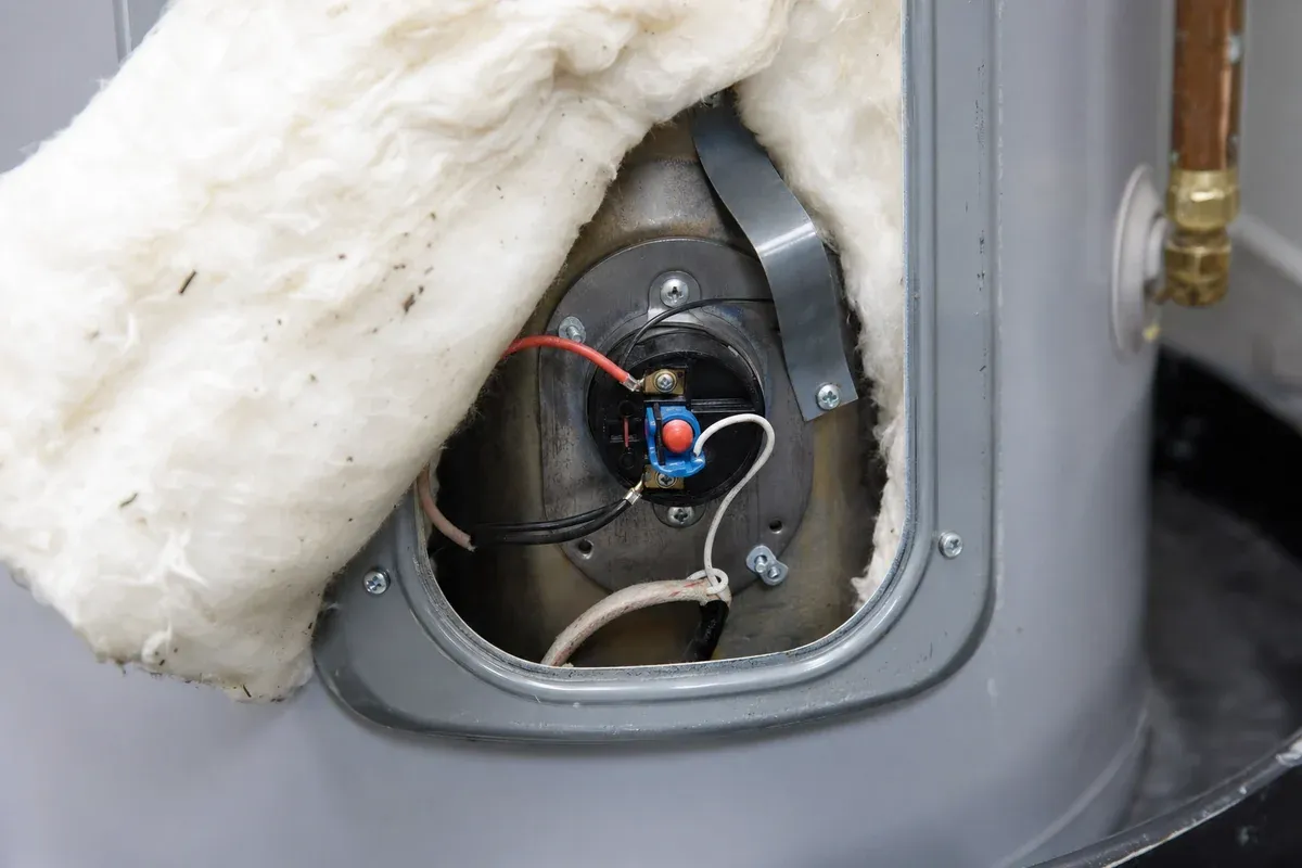 Electric water heater repair in Orange County, upper access panel off with thermostat and reset visible