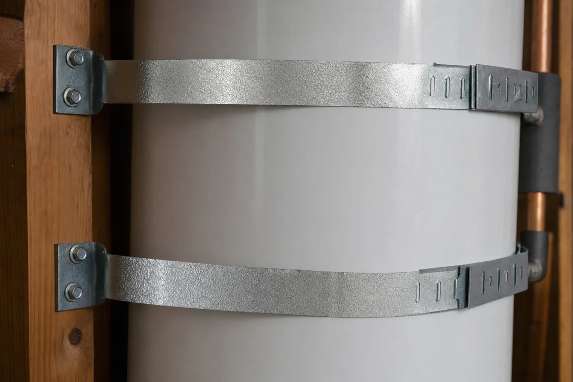 Two galvanized seismic straps on a water heater, required by California code